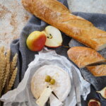 Artisan French baguette, cheese, knife, and grains arranged on a table
