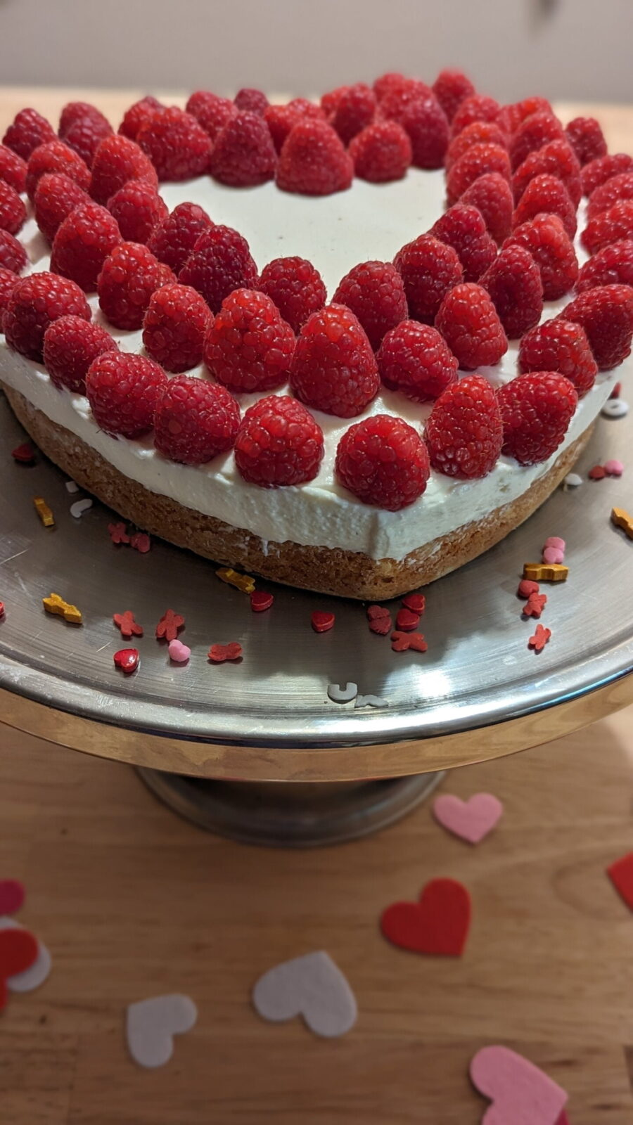 This picture shows the creamy raspberry heart cake 08 from front with sprinkles on plate