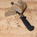 this picture shows the oil seed bread cut in half with a knife underneath