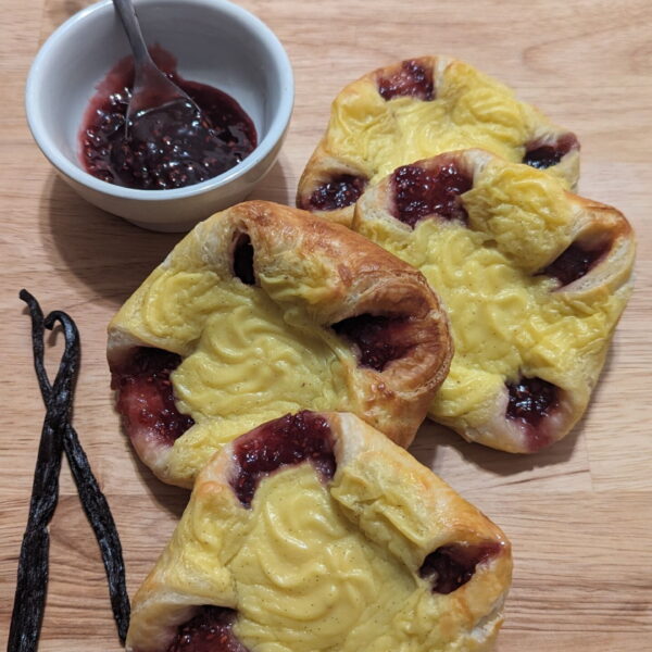This picture shows 4 sweet vanilla raspberry danish with 2 vanilla beans