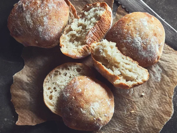 This image shows our sourdough ciabatta buns on a cutting board, show casing the nice texture of the bun