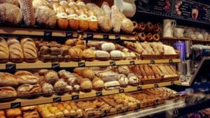 Display of various traditional German breads and pastries in a bakery, featuring rustic loaves, rolls, and pretzels on wooden shelves